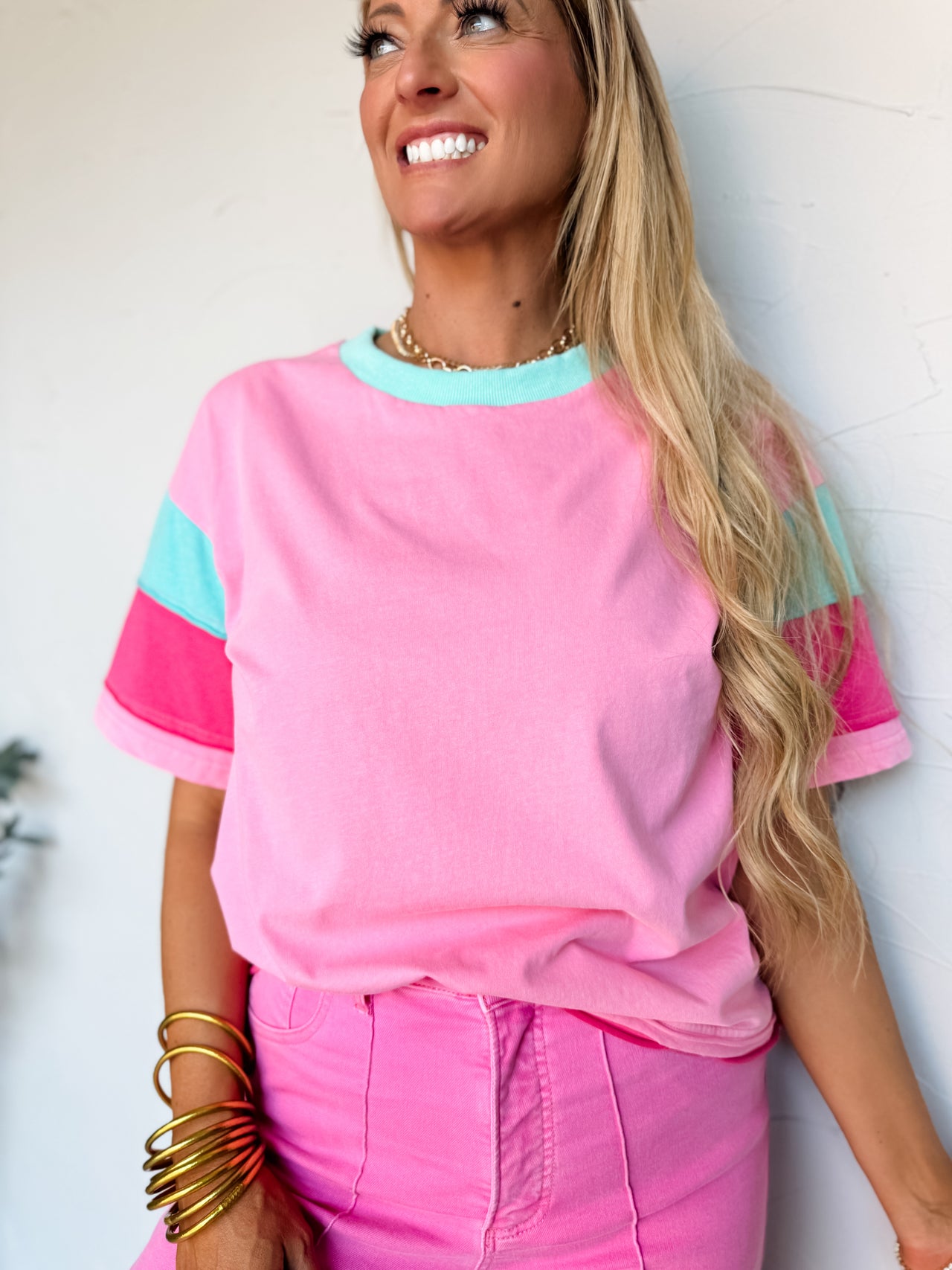 Woman wearing a pink and blue top with pink pants against a white background