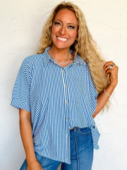 Woman wearing a blue and white striped button up shirt and jeans against a white background