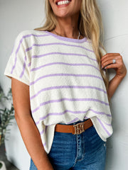 Woman wearing a white and purple striped shirt with blue jeans against a white background