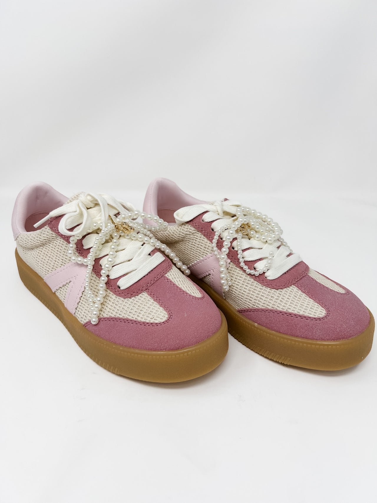 Pink and white sneakers with brown soles on a white background