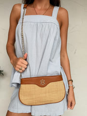 Woman holding a brown and beige handbag against a neutral background