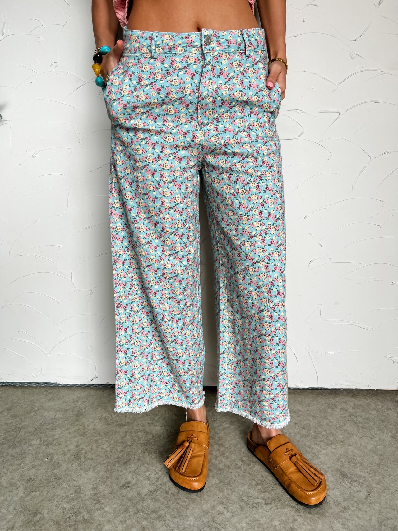 Person wearing floral patterned pants with a white background