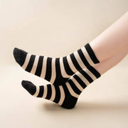 Black and white striped socks worn by a person on a beige background