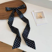Black polka dot headband on a wooden board with a white surface underneath