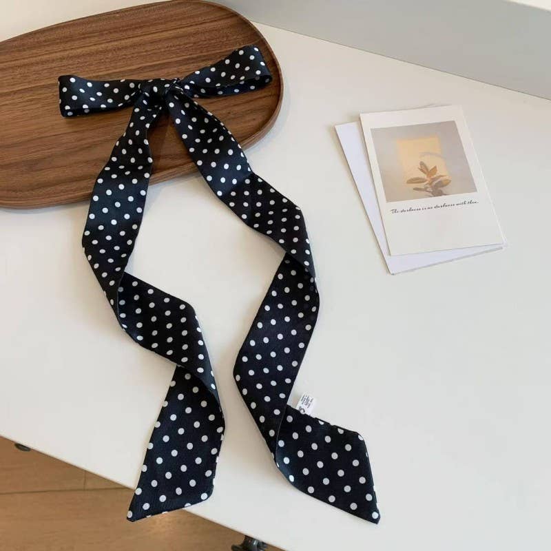 Black polka dot headband on a wooden board with a white surface underneath