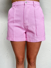 Pink shorts worn by a person against a white wall
