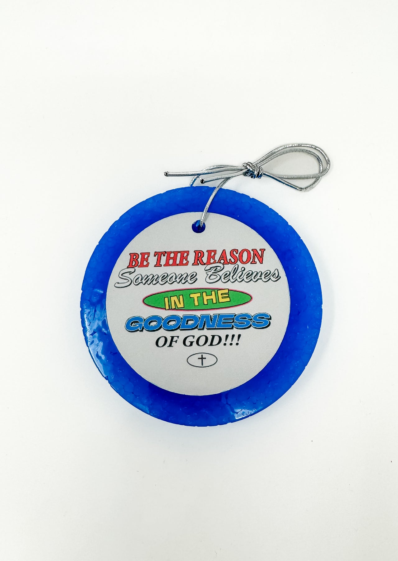 This "Be The Reason Someone Believes In The Goodness Of God!!!" car freshie features an inspiring, round design with a bold faith-based message and a small cross at the bottom, all framed by a smooth, circular outer border. It comes ready to hang from your rearview mirror with an attached silver string. Colors and scents vary.
