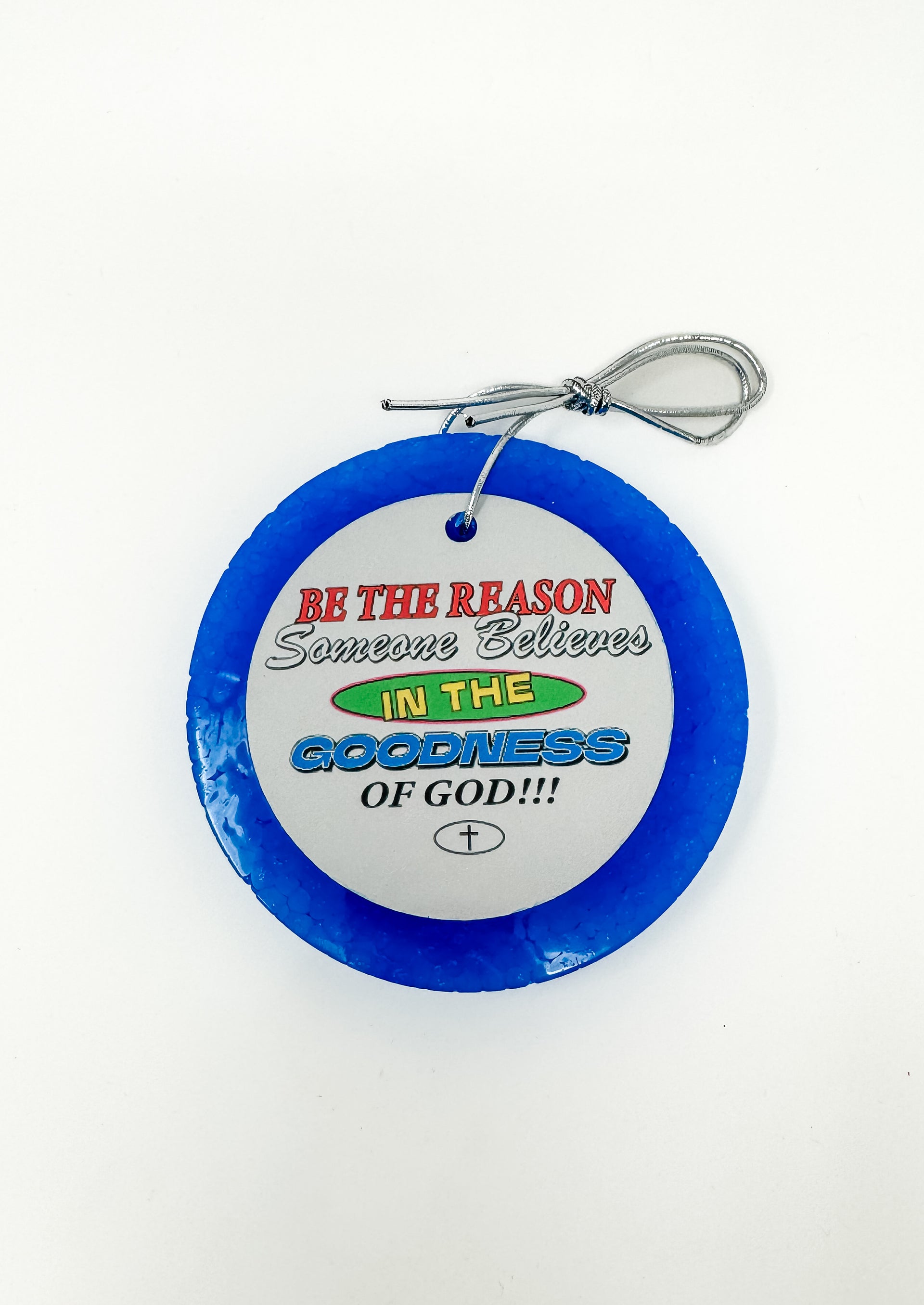 This "Be The Reason Someone Believes In The Goodness Of God!!!" car freshie features an inspiring, round design with a bold faith-based message and a small cross at the bottom, all framed by a smooth, circular outer border. It comes ready to hang from your rearview mirror with an attached silver string. Colors and scents vary.