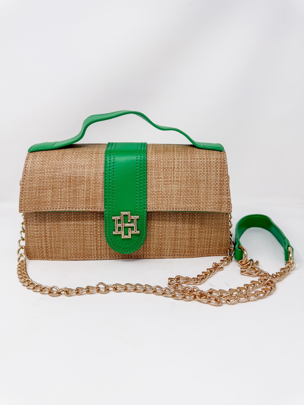 Woven handbag with green accents and a gold chain on a white background