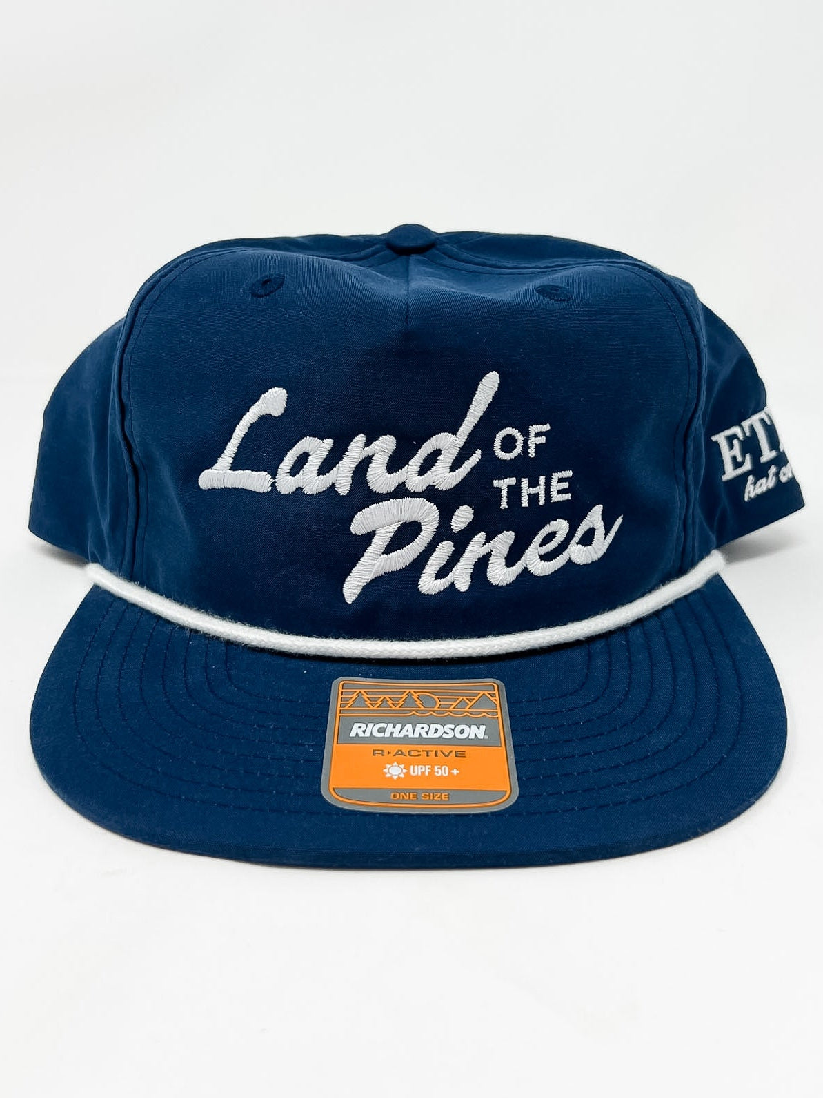Navy blue cap with 'Land of the Pines' text on a white background