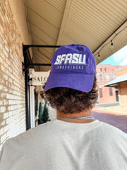 Person wearing a purple 'SFASU Lumberjacks' cap outdoors.