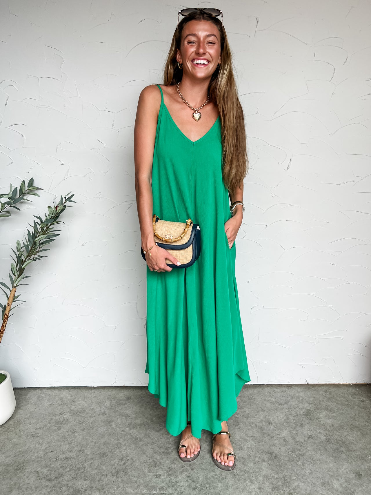 Girl in long green dress in front of plain wall 