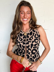 Woman wearing a leopard print top and red pants against a white wall