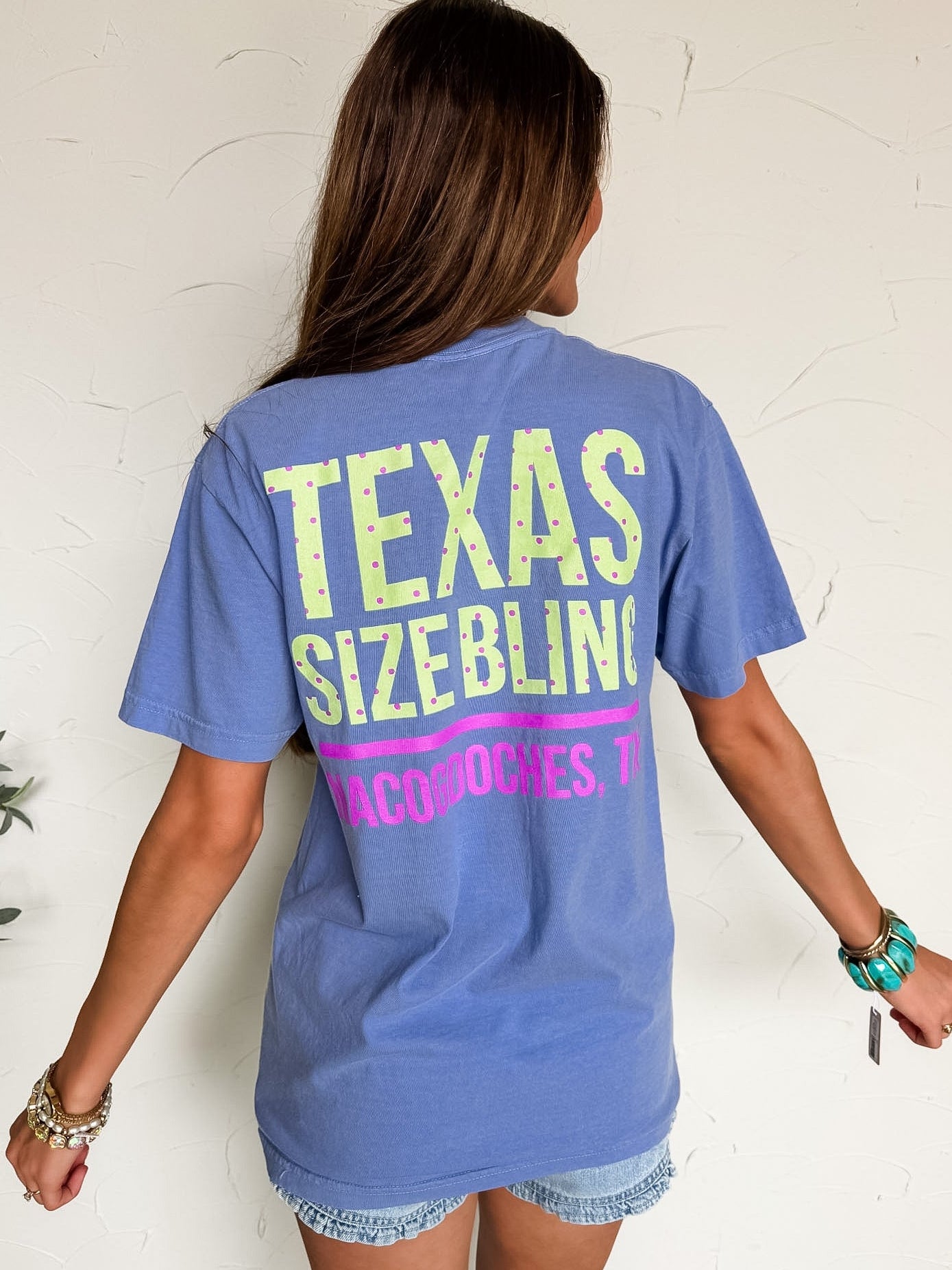 Person wearing a blue t-shirt with 'Texas Size Bling' text on a white background