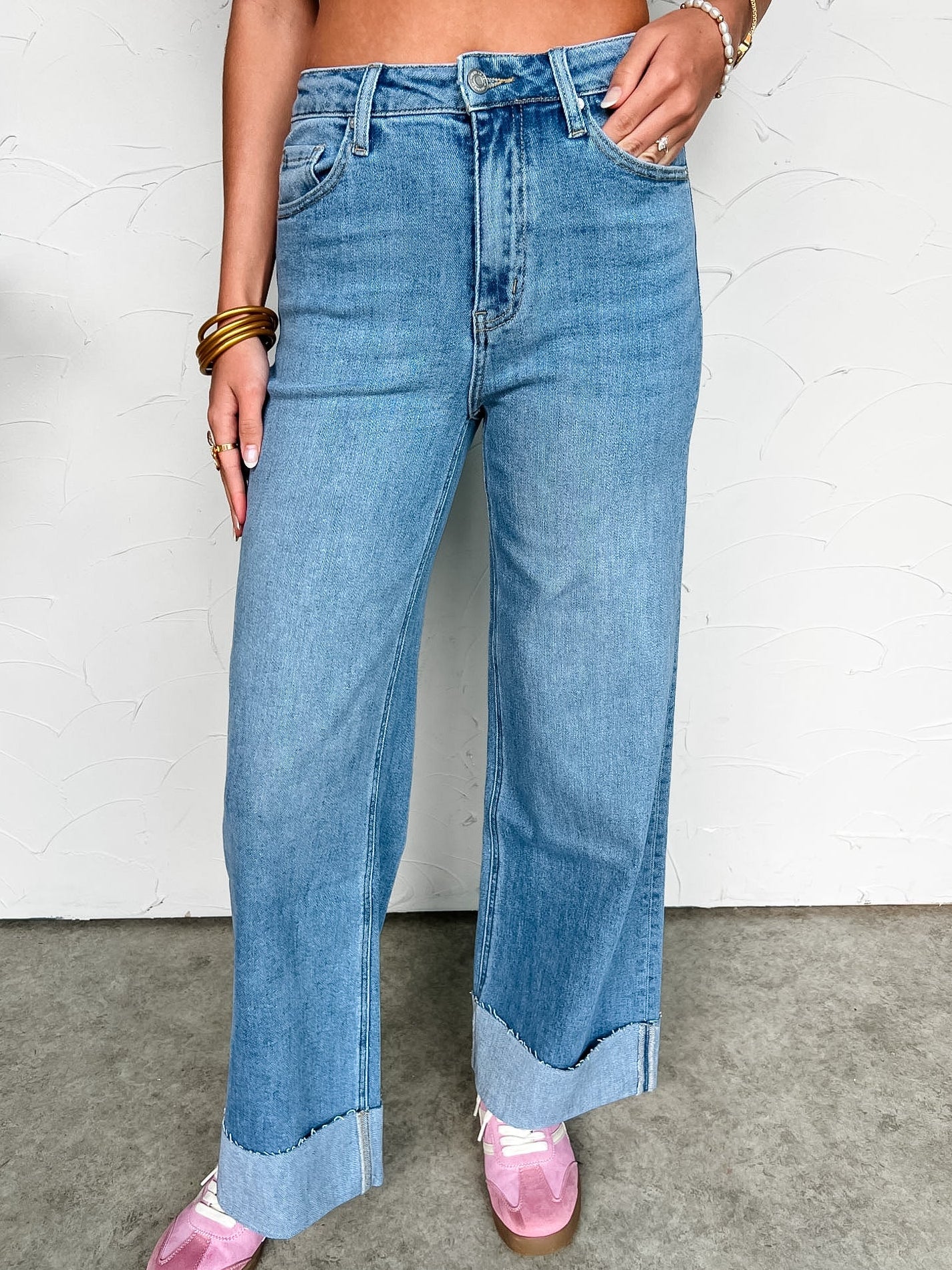 Person wearing blue jeans with a cuff hem with a white background