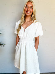 Woman wearing a white dress against a white wall
