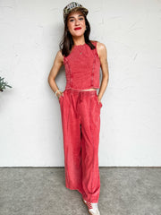 Woman wearing a red acid washed  set and cap against a white wall
