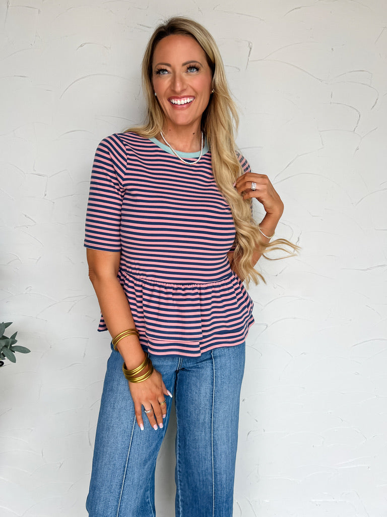 Woman wearing a striped shirt and jeans against a white wall