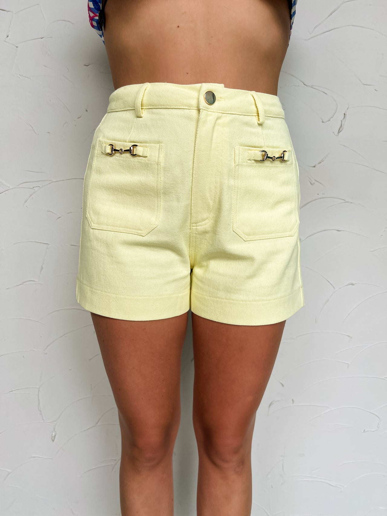 Light yellow shorts worn by a person on a textured white background