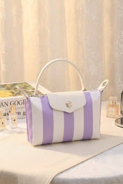 Purple and white striped handbag on a surface with a blurred background