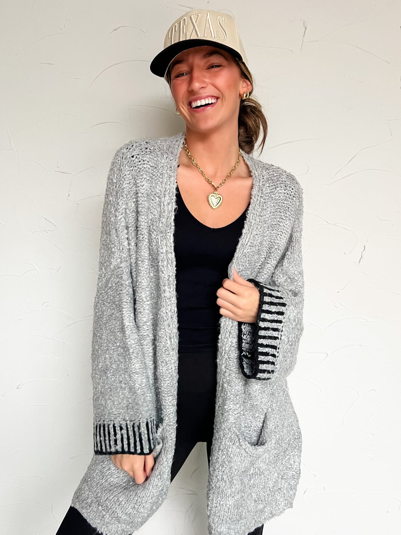 Person wearing a gray cardigan over a black top with a white background