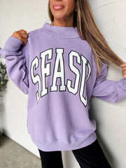 Person wearing a purple sweatshirt with 'SEAS' text against a white wall.