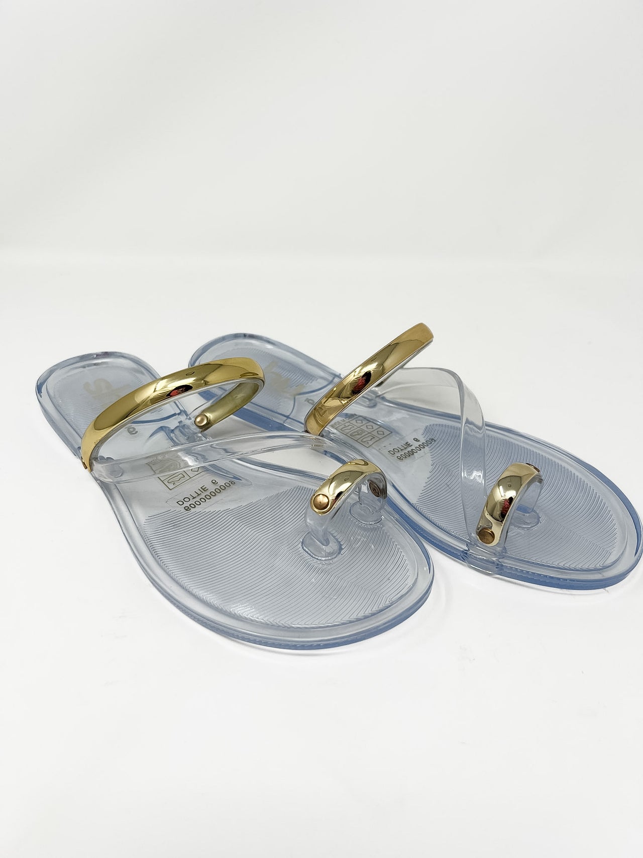 Clear jelly sandals with gold straps on a white background