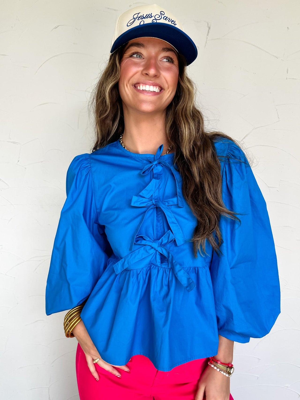 Woman wearing a blue blouse and pink pants with a white background