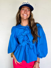 Woman wearing a blue blouse and pink pants with a white background