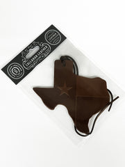 Brown leather air freshener shaped like the state of Texas with a star, on a white background.