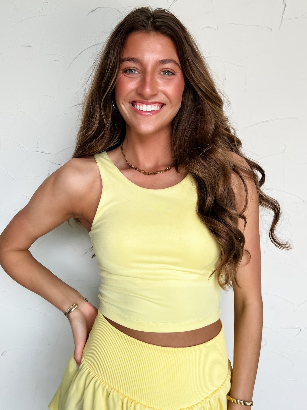 Woman wearing a yellow tank top and skirt against a white background