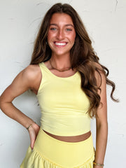 Woman wearing a yellow tank top and skirt against a white background