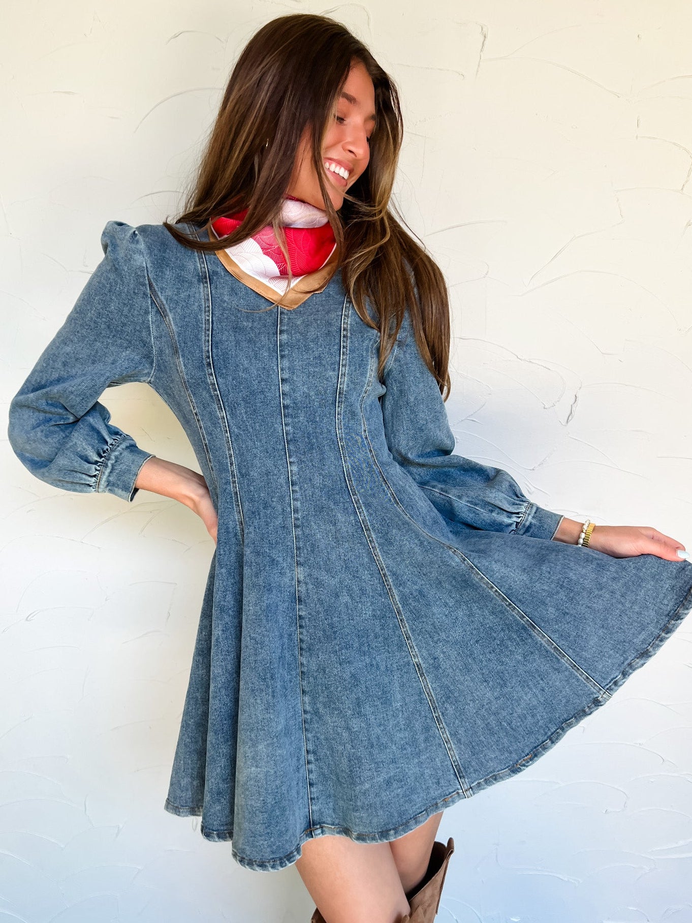 Woman wearing a denim long sleeve dress against a white wall