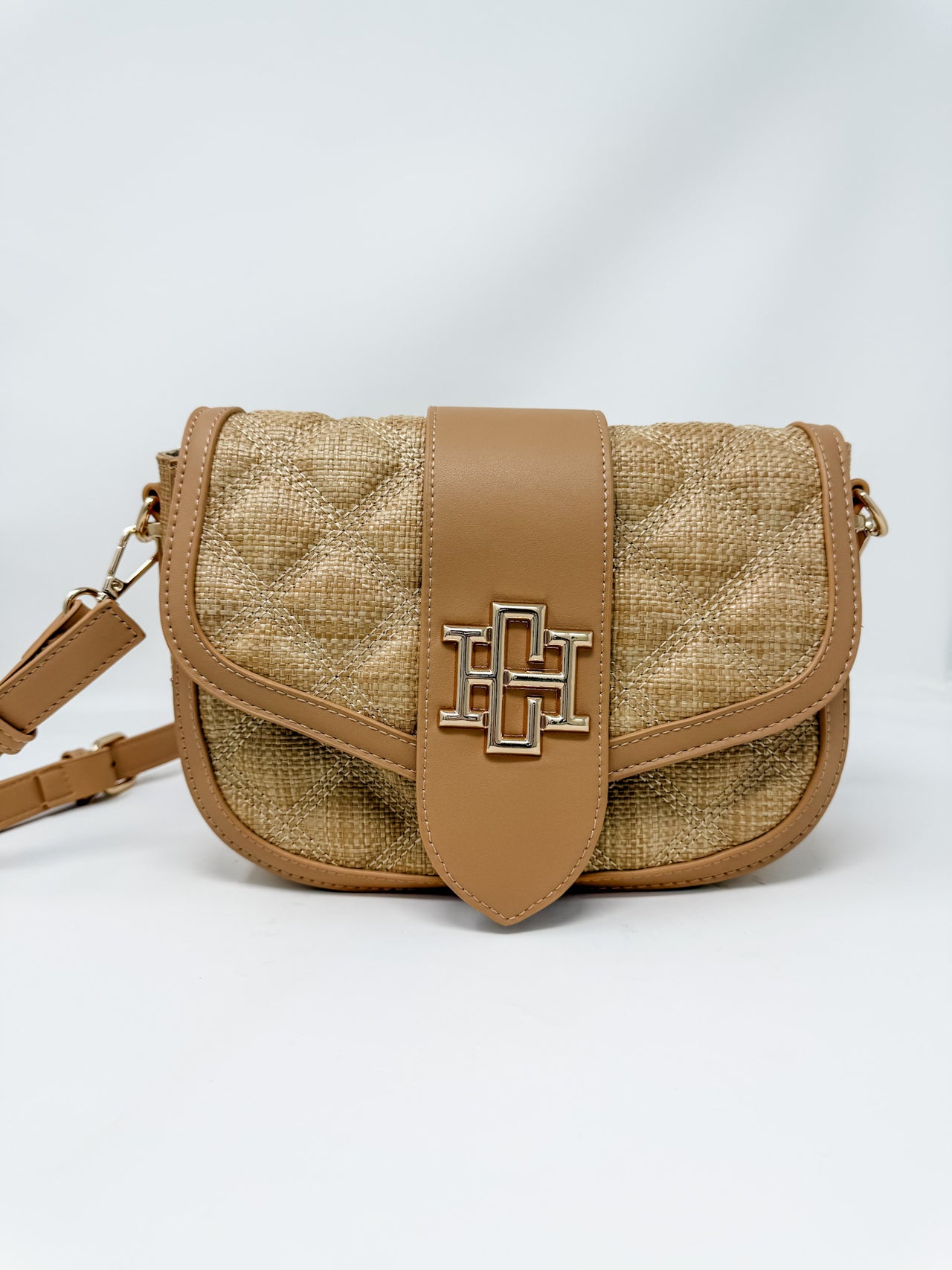Brown woven handbag with leather accents on a white background
