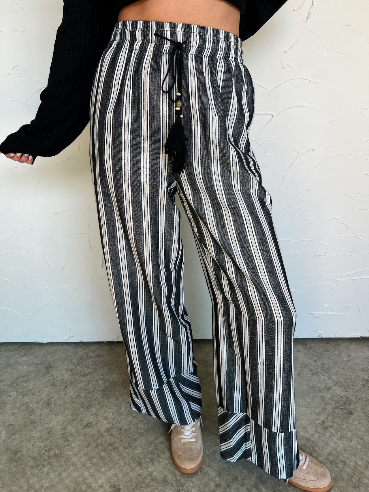 Person wearing black and white striped pants with a plain background