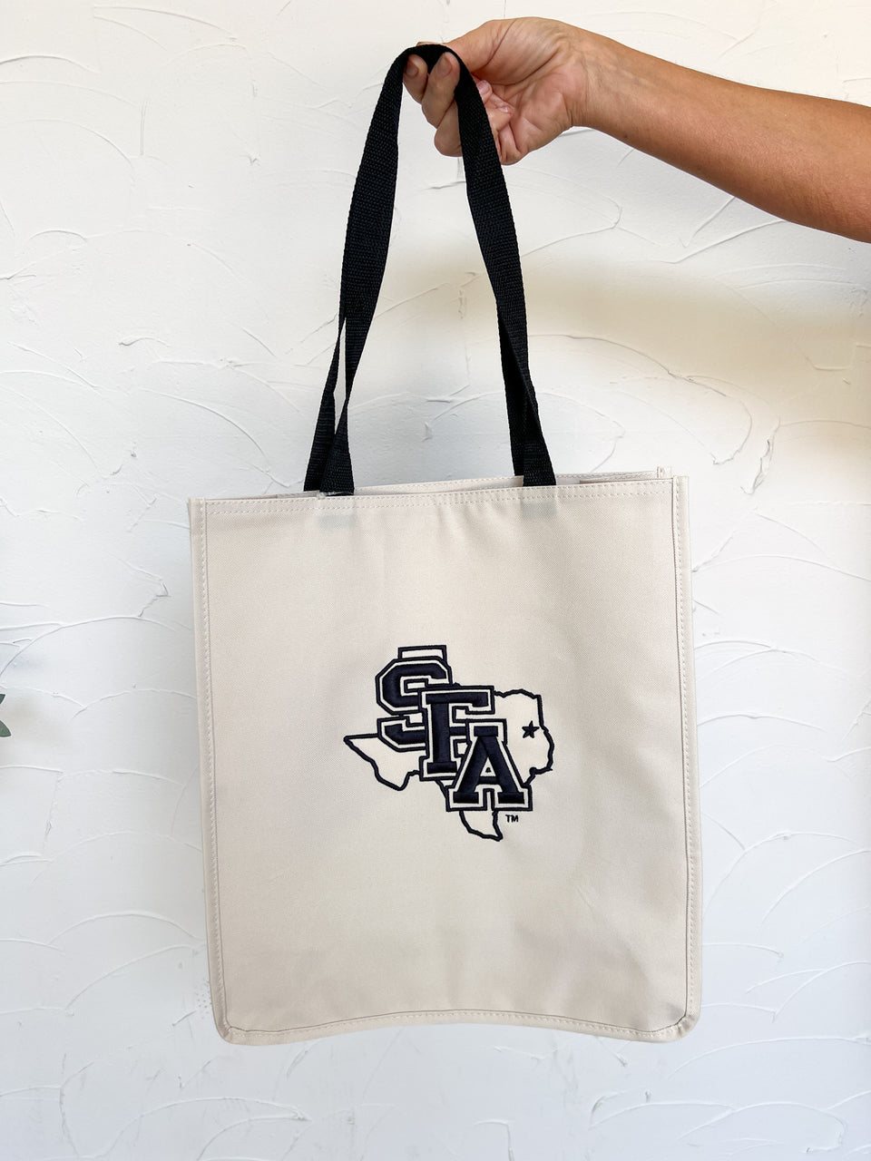 a hand holding a white bag with a logo on it