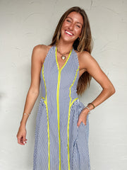 Woman wearing a blue and white striped dress with yellow accents against a white background