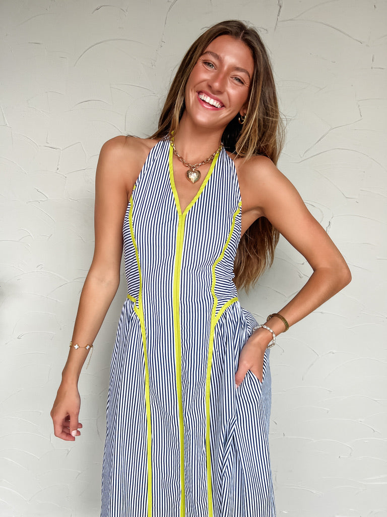 Woman wearing a blue and white striped dress with yellow accents against a white background