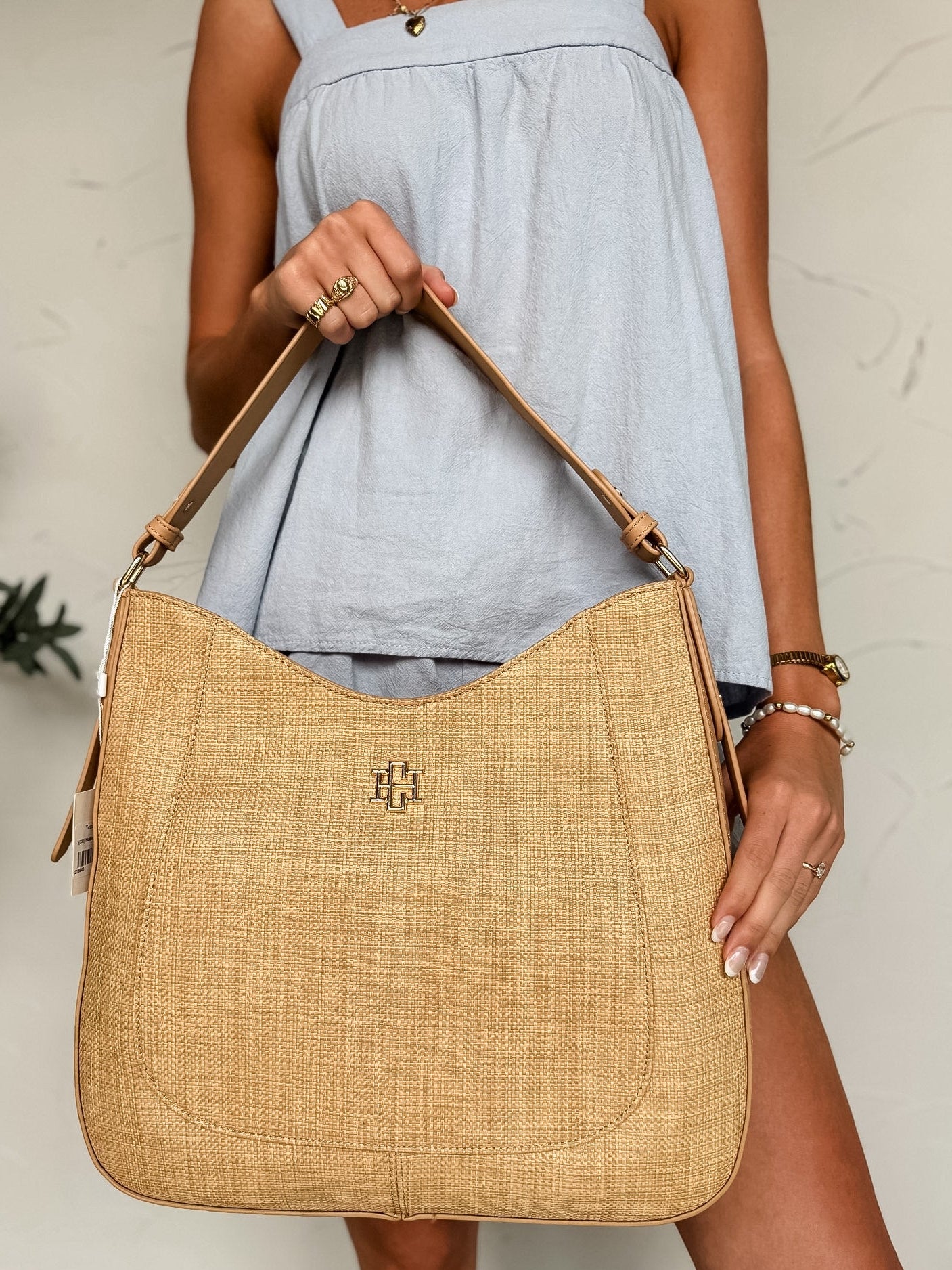 Person holding a woven handbag with a visible brand logo against a neutral background