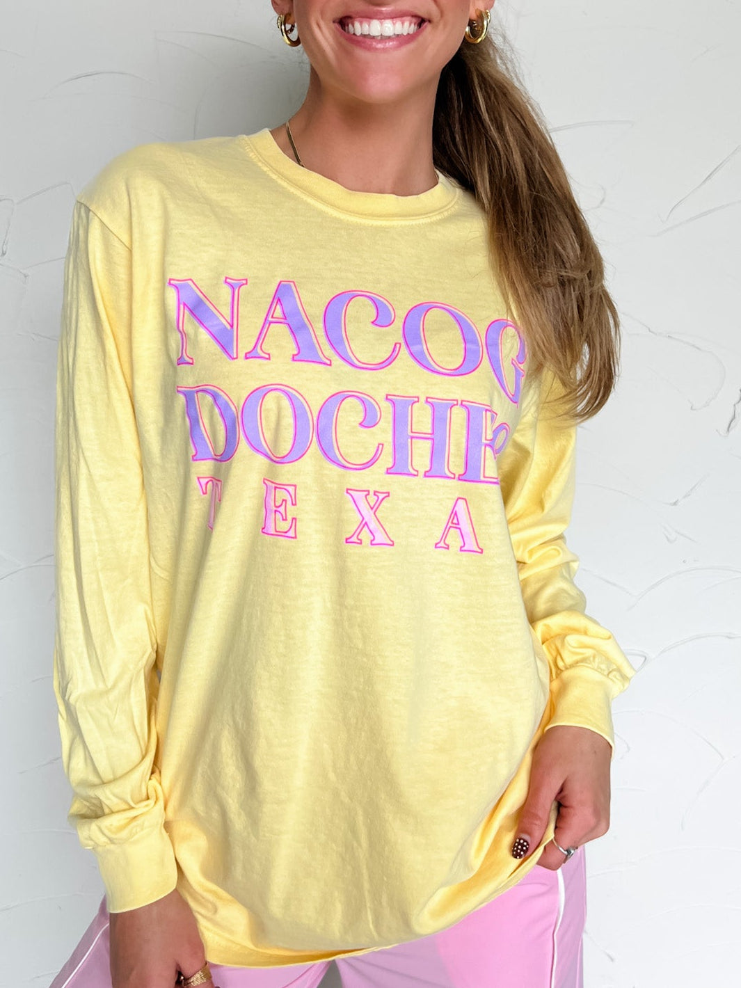 Woman wearing a yellow long-sleeve shirt with 'Nacogdoches, Texas' text against a white background
