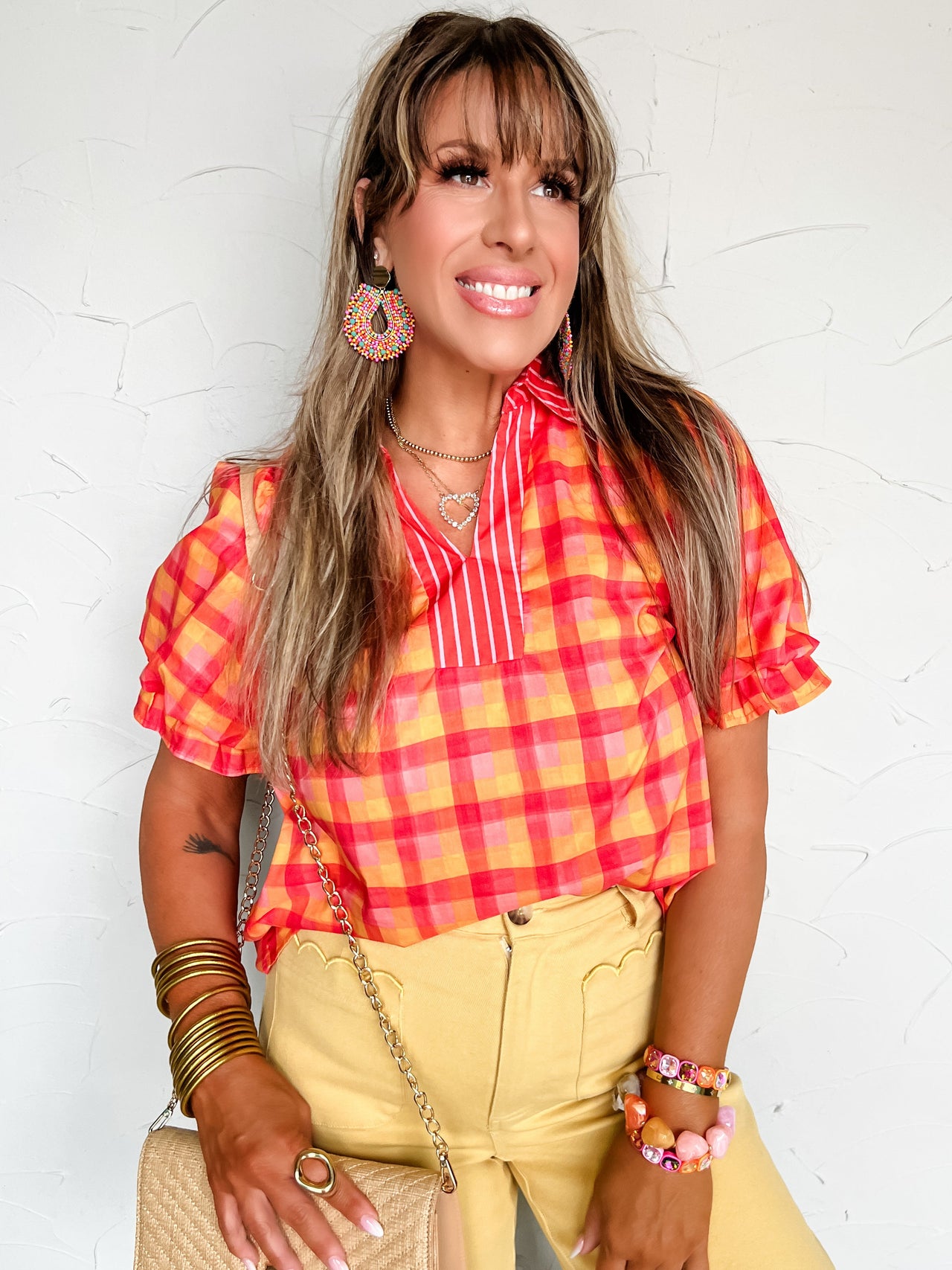 Woman wearing a red and orange plaid shirt with yellow pants against a white background