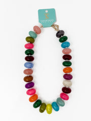 A multicolor beaded necklace with glossy, oval-shaped beads in various vibrant colors, displayed on a white background with a turquoise brand tag that reads 'Taylor Shave Boutique'.