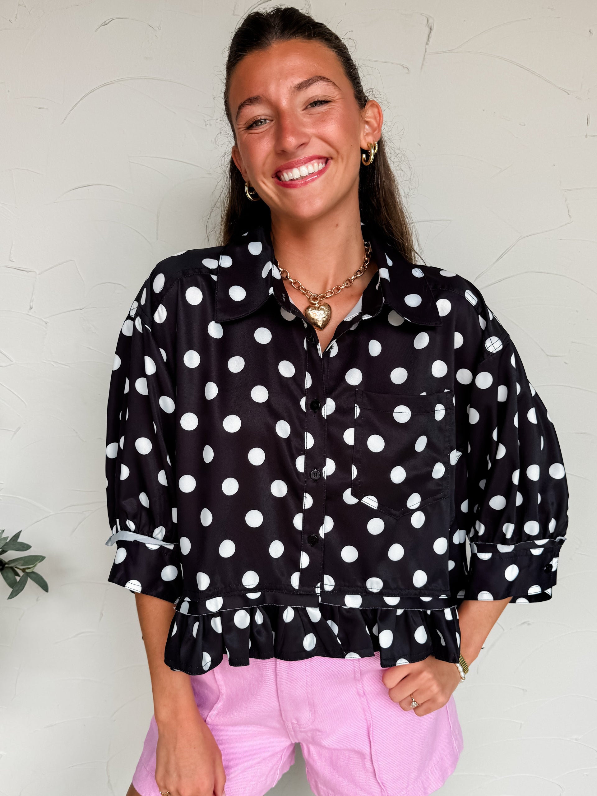 woman wearing a back blouse with white polka dots and pink shorts