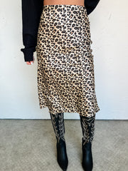 Person wearing a leopard print midi skirt with black boots on a plain background