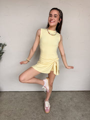 Young girl in a yellow dress posing against a plain wall.