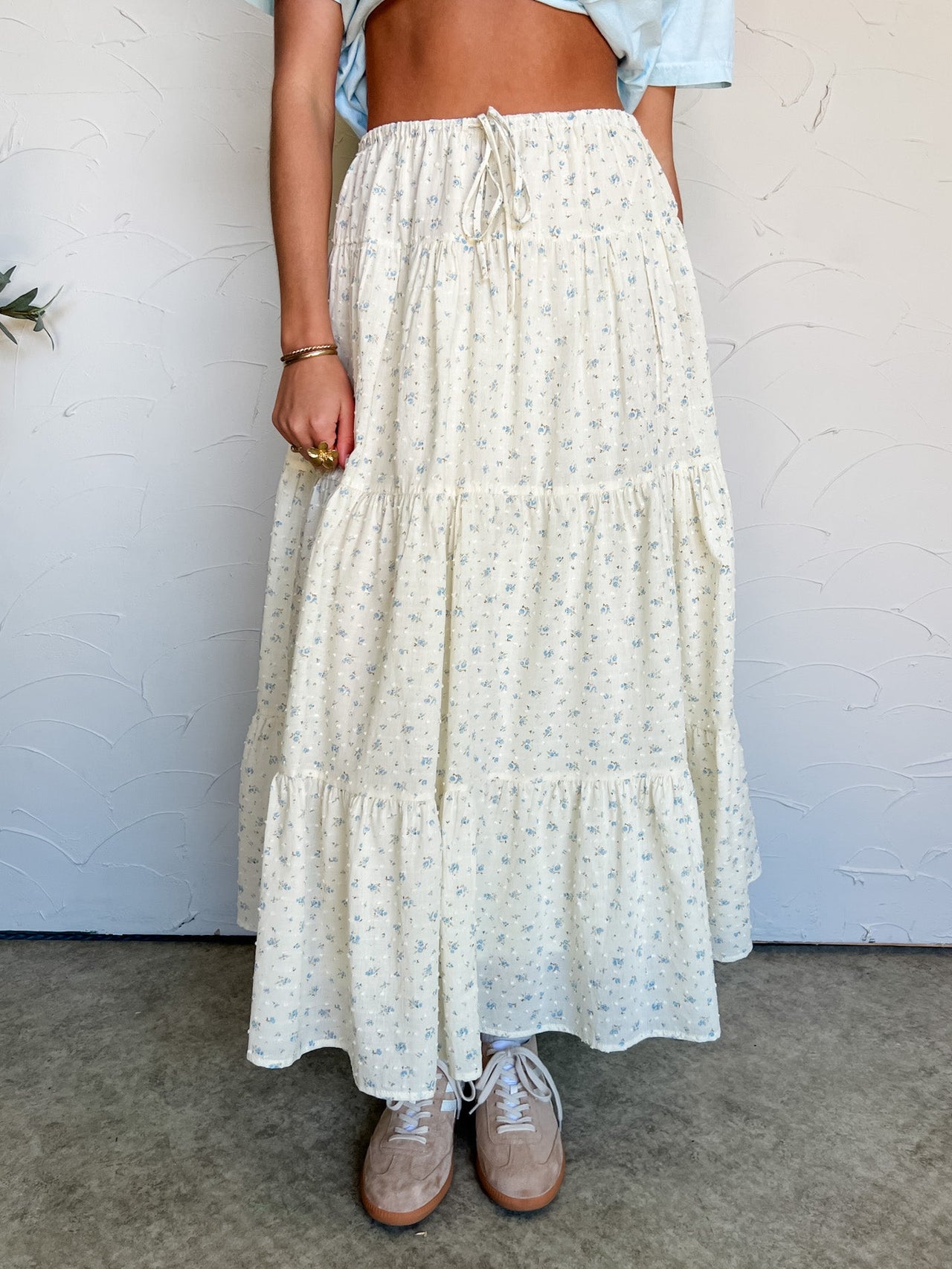 Person wearing a long, light-colored skirt with a white background