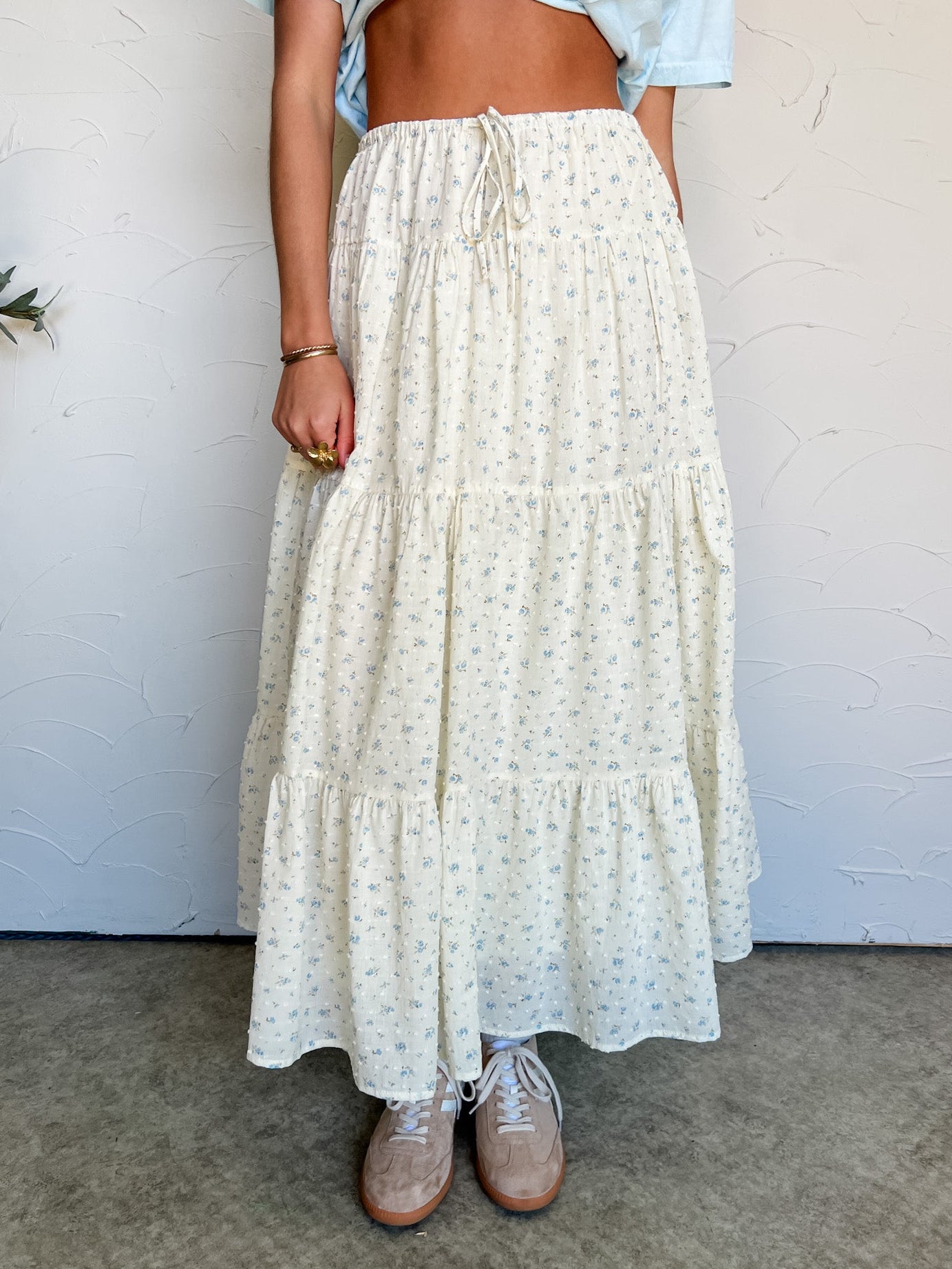 Person wearing a long, light-colored skirt with a white background