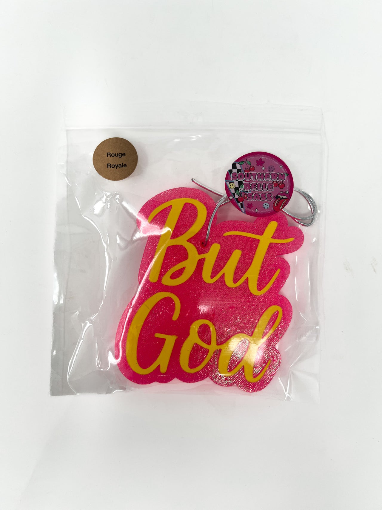 Pink and yellow 'But God' air freshener in packaging on a white background