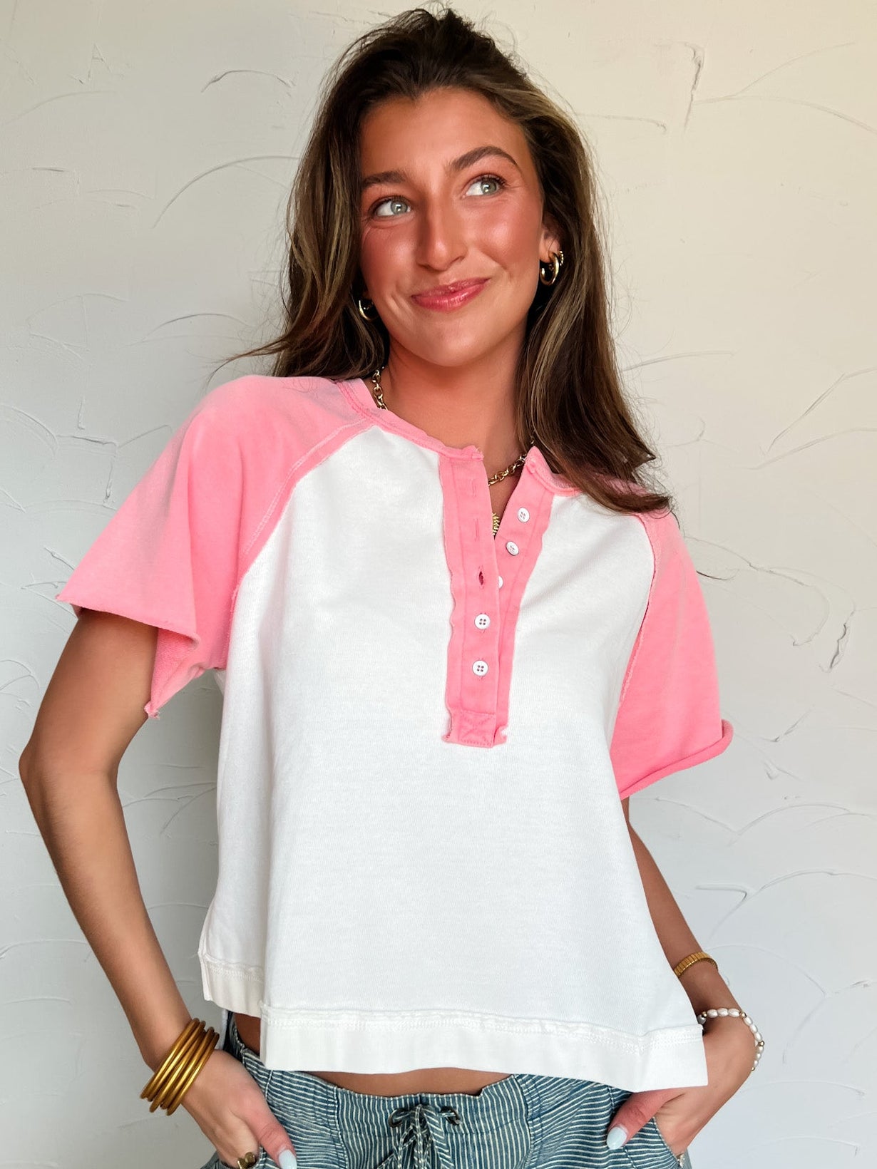 Woman wearing a white and pink baseball-style shirt against a plain background