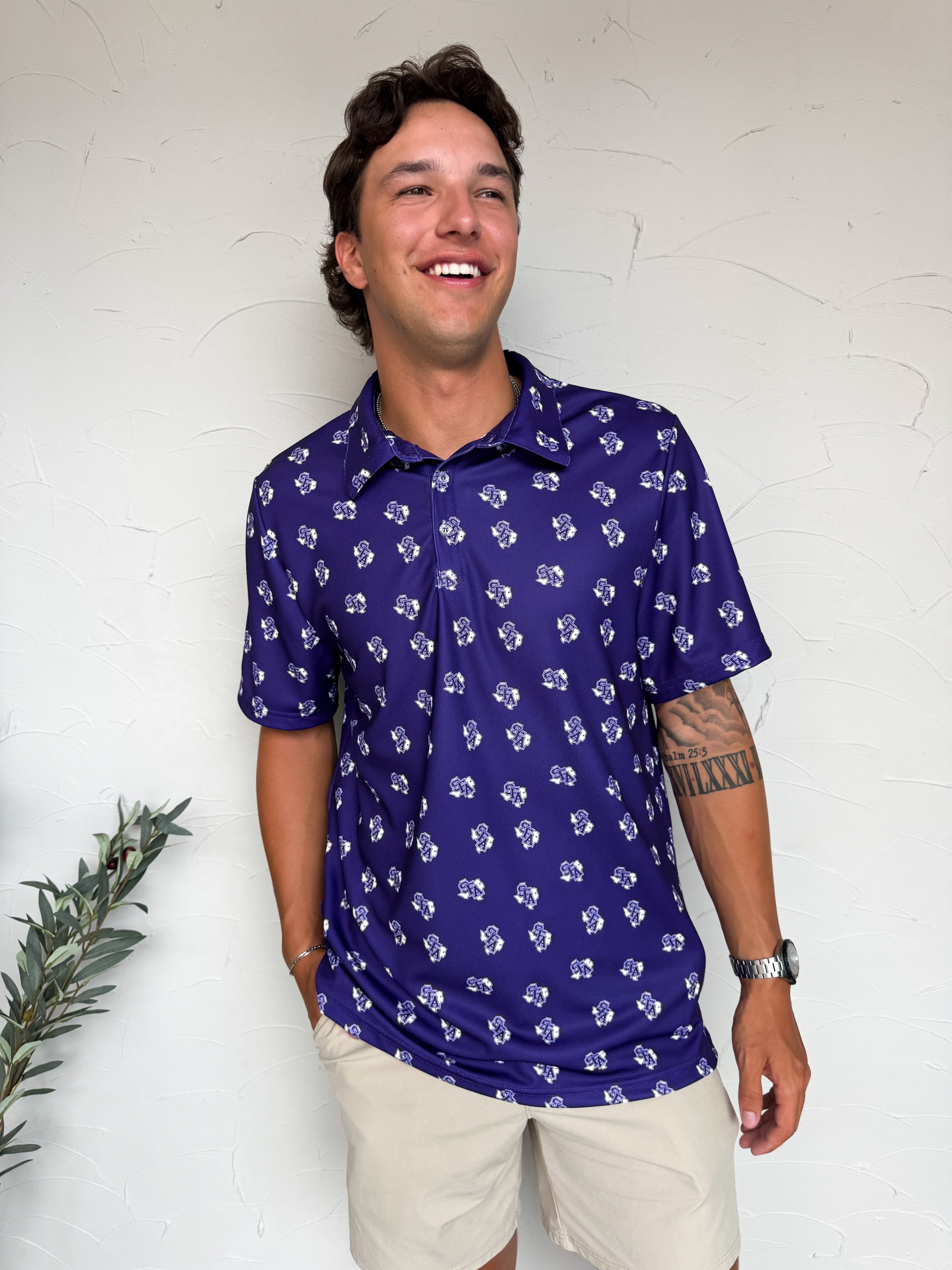 Man wearing a purple patterned polo shirt against a white wall